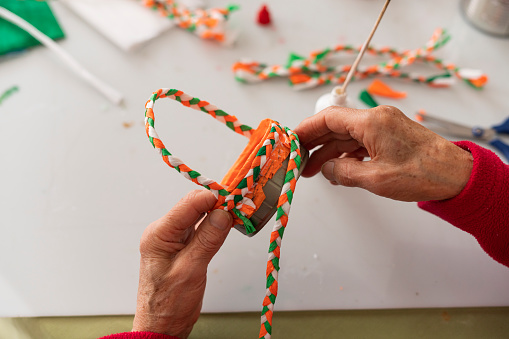 Hands of an elderly Latina from Bogota Colombia between 70 and 74 years old, making a craft with materials in her living room