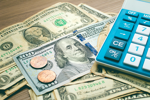 United States dollar bills, 1 cent coins and a blue calculator. Finance and economics concepts.