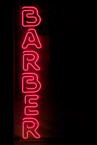 Barbershop old fashioned sign, red neon light. Copy space on the right. Galicia, Spain.