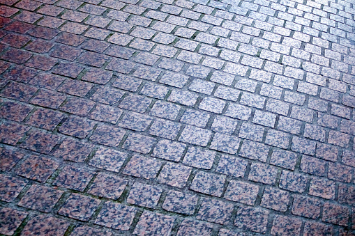 Granite stone cobblestone pavement, diminishing perspective, full frame image suitable for background.