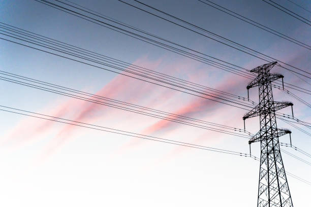High-voltage lines of communication towers under the burning clouds at sunset stock photo