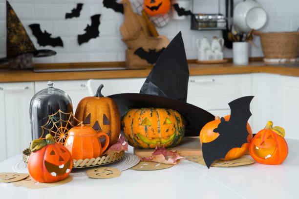istock Happy Halloween! Pumpkin Jack on the table. Lantern with a carved smile and different attributes of the holiday on a light background in the interior. For family holidays at home. Copyspace. 1414650751