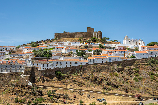 May 23, 2022: A View of Mertola, Portugal, from the far bank of the Guadiana River on a sunny, spring afternoon. Mertola is an old and beautiful white village in the heart of a natural reserve, with amazing views and located at the highest navigable point of the Guadiana River.