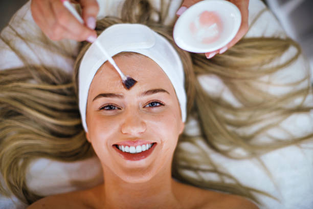 Enjoying beauty treatment. Unrecognizable beautician applying facial mask or chemical peel on a young woman at beauty salon. facial chemical peel stock pictures, royalty-free photos & images