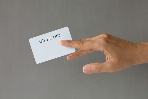 Close-up of a card in a woman's hand isolated on gray.