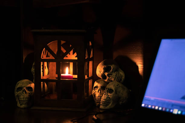 istock Halloween room interior workspace table with laptop lighting screen and background center of composition scene with candle in vintage lantern and decorative skulls 1414664676
