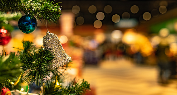 Christmas tree with decorative bell in shopping mall on holidays eve season time of selling gifts, advertising panoramic picture concept with unfocused background for copy space of your text