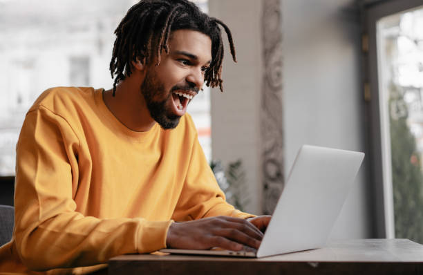 Excited African American man playing video games online stock photo