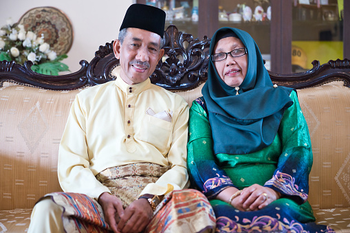 Malaysian couple dressed traditionally smiling at the camera for a formal photograph
