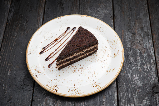 chocolate cake with cream and nuts on a wooden background