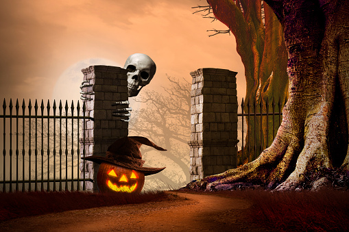 A skeleton an an illuminated jack o'lantern stand guard at a gated entrance that is framed by gnarled bare trees on Halloween night as a full moon rises in the misty distance.