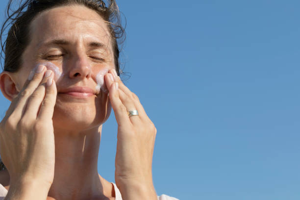 istock Woman is applying sun cream on her face 1414678685