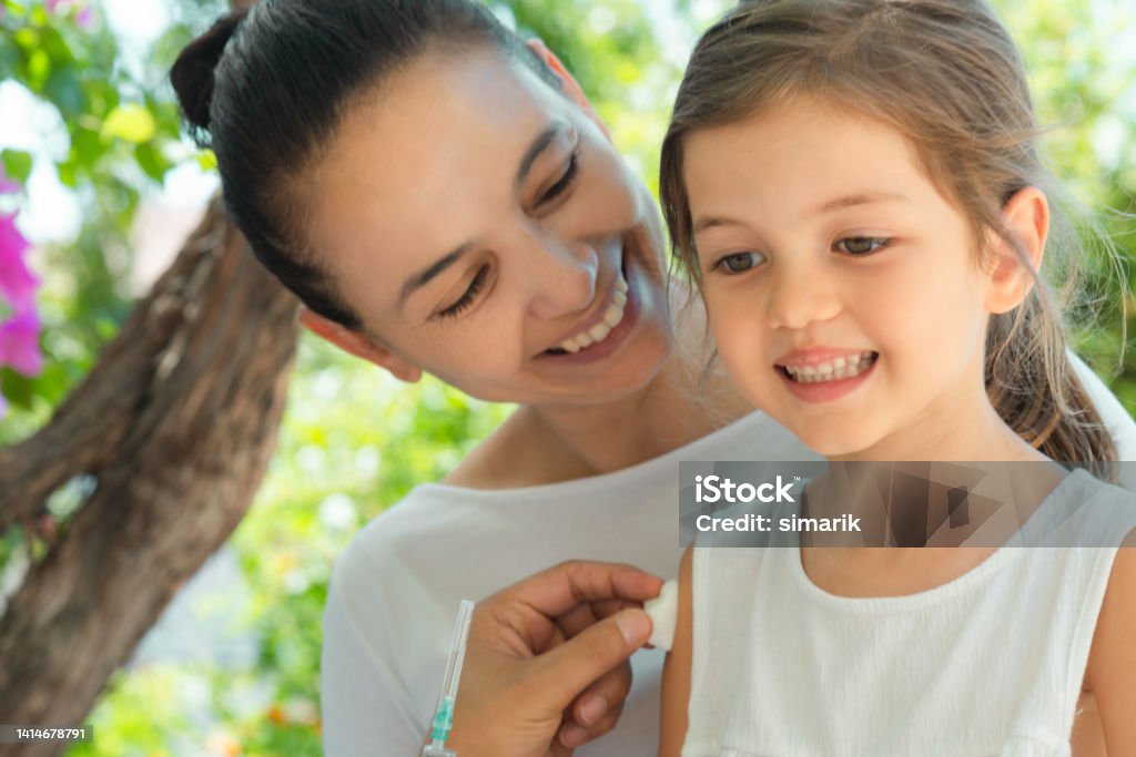 Vaccination Child is sitting in her mothers lap and  is getting vaccination from a doctor. Polio Stock Photo