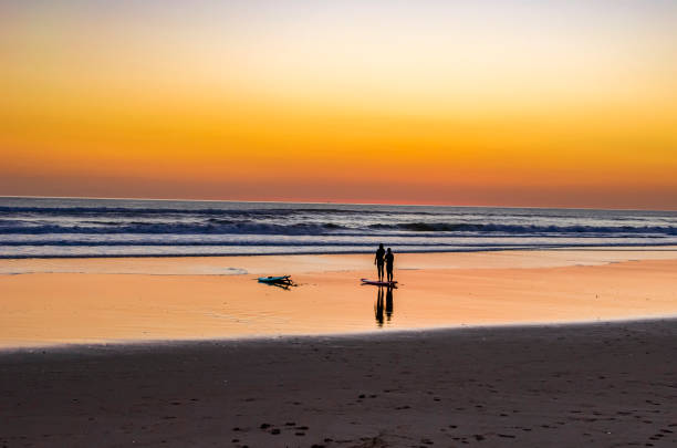 istock Surfers on the beach at sunset 1414685918