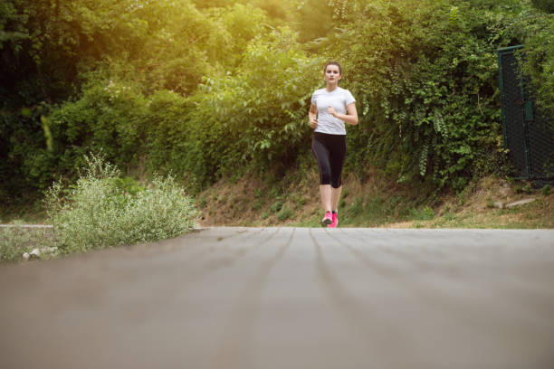 istock Woman Runner Running Through The Spring Park Road 1414688877