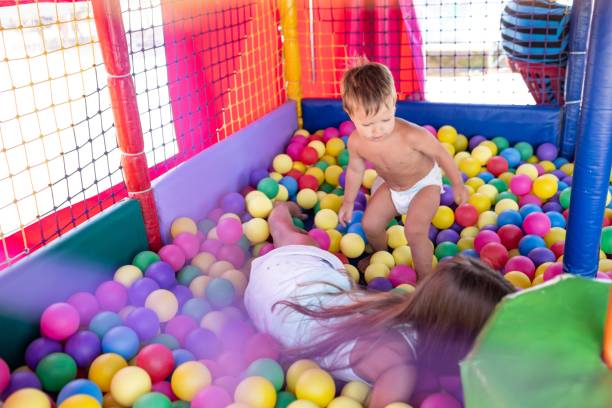 istock The older sister plays with her younger brother and throws small balls at him while sitting in the playroom 1414689152