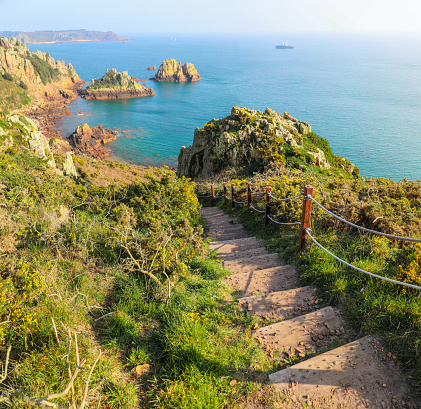 Steps along hiking trail down to the beautiful blue ocean along the coastline of Jersey in the Channel Islands United Kingdom