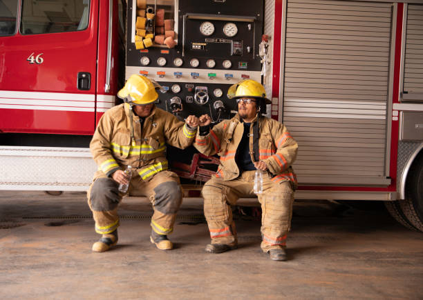 two firefighters in fire station - bombeiro imagens e fotografias de stock