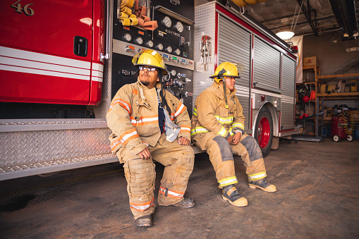 Two male firefighters drink some water after a long day at work. They are tired and exhausted from fighting fires on the Navajo Reservation, Utah.