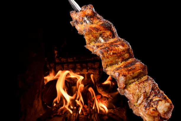 Barbecue pork ribs on skewers with fire in the background. Brazilian food. stock photo
