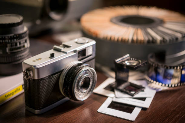 Old photo camera with blurred slide projector in the background. Old photo camera with blurred slide projector in the background. slide projector photos stock pictures, royalty-free photos & images