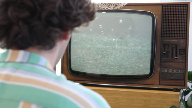 Young man watching an old vintage tv