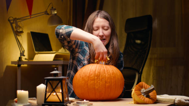 Woman carving Jack O Lantern pumpkin for Halloween stock photo