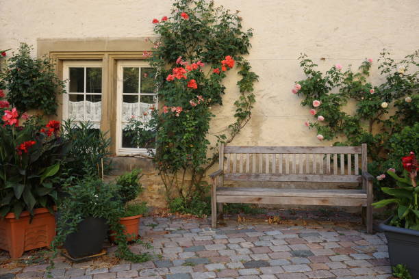 istock Bench with flower pots and closed decorated window in old house 1414699806