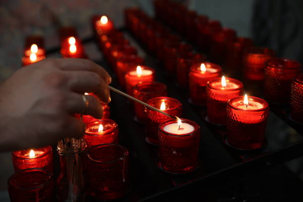 istock Hand lighting up a candle with a long match in catholic church 1414700452