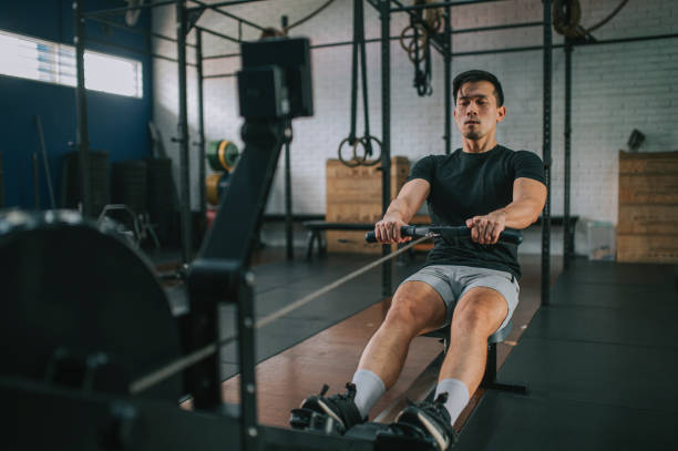 Asian Chinese Gay man exercising on rowing machine in a gym stock photo