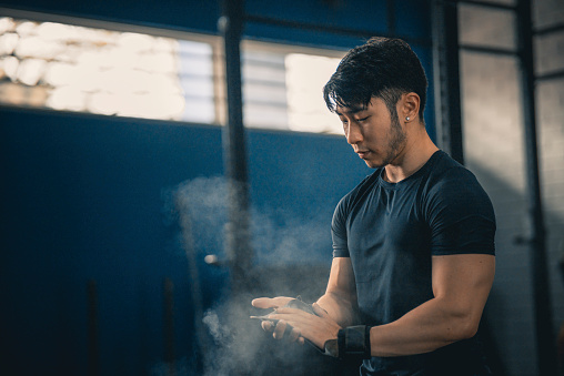 Asian Chinese gay man getting ready putting on talcum powder before gym strength training
