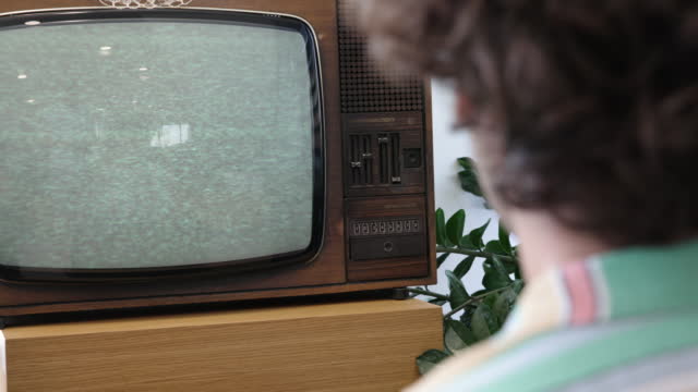 Young man watching an old vintage tv