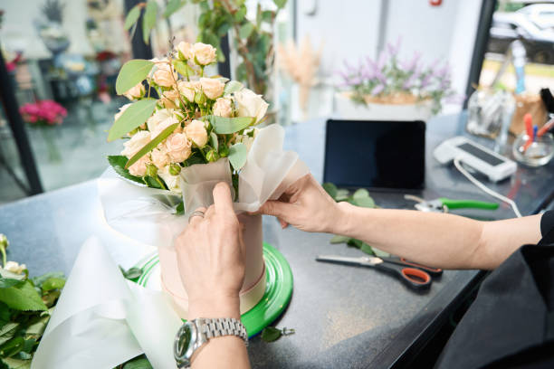 istock Female florist inserts decorative paper into round box with bouquet 1414722236