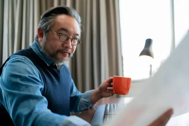 Mid adult man working at home on holiday,Home Office: a Happy Young Asian freelance creative man Working in the Comfort of His Home, Social Distancing Concept