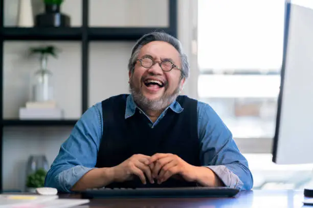 Mid adult man relax after working at home on holiday,Home Office: a Happy Young Asian freelance creative man Working in the Comfort of His Home, Social Distancing Concept