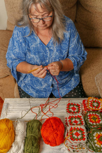 istock older white-haired woman crocheting 1414726019