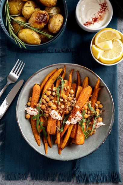 Sweet roasted carrots with sauce and green herbs, close up. Festive dish for celebration Thanksgiving Day. Top view, Flat-lay