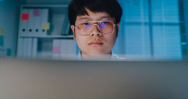 istock Close-up Young Asian businessman using laptop computer look at screen focus checking reporting presentation at small business workplace overtime at night. 1414734754