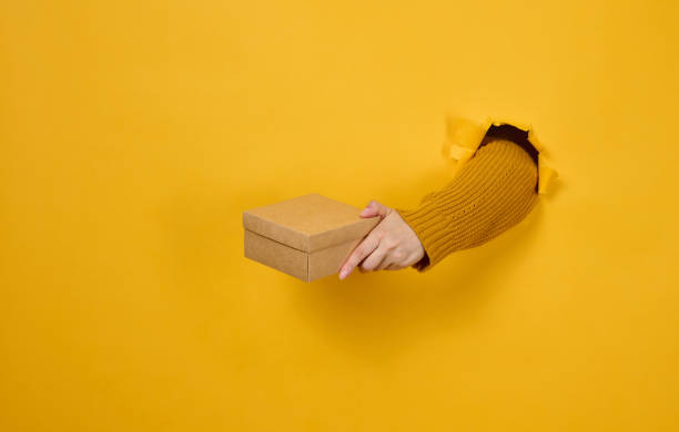 istock A woman's hand holds a brown cardboard box 1414735010
