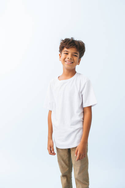 Half length portrait of a carefree Indian boy against bluish white background Half length portrait of a carefree Indian boy against bluish white background. He is wearing white T shirt. looking to the side. bluish white stock pictures, royalty-free photos & images