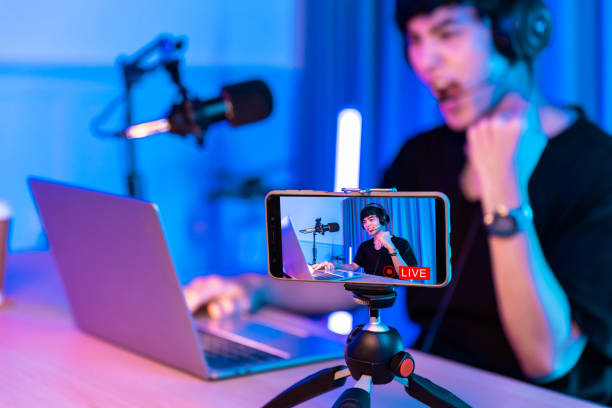 Playing video games on smartphone. Young asian handsome man sitting on chair holding cellphone in his hand. Exited streamer wearing headset in online mobile game in neon room .Esport streaming game online, Home quarantine .activity. jugar videojuegos en el teléfono inteligente. joven asiático guapo sentado en la silla sosteniendo el teléfono celular en la mano. streamer salió con auriculares en el juego móvil en línea en la habitación de neón. esport juego de transmisión en l