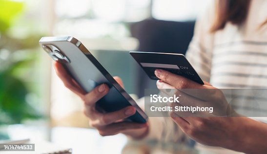 istock Woman hand holding credit cards and using smartphone for shopping online with payment on internet banking. 1414744533