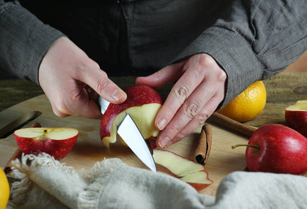 istock A woman peels a red apple with a knife. 1414745015