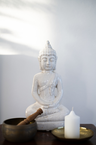 White ceramic Buddha with Tibetan singing bowl and candle