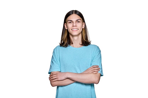 Portrait of confident smiling teenage guy looking at camera on white isolated background. Handsome young male with crossed arms posing in studio. Youth, students, people concept
