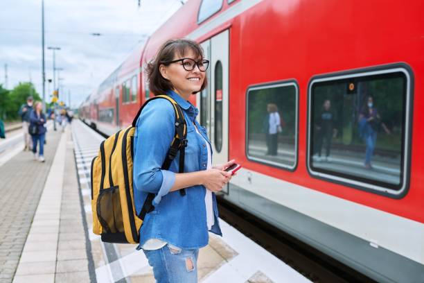 Woman passenger waiting for commuter train at station outdoor platform stock photo
