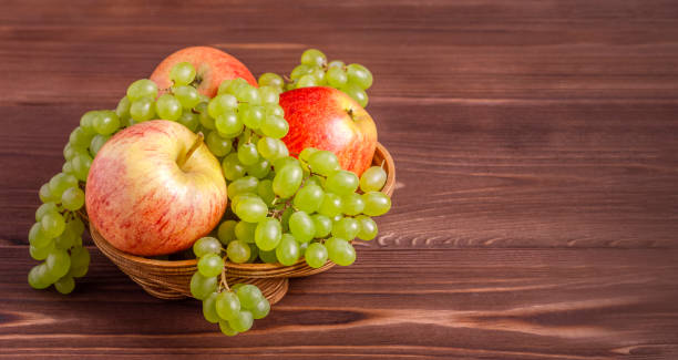 istock Apples and grapes in a wooden basket. 1414756412