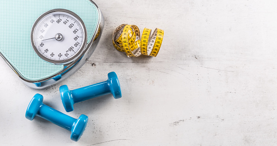 Weight scale and dumbbells with measure tape on floor - Top of view.