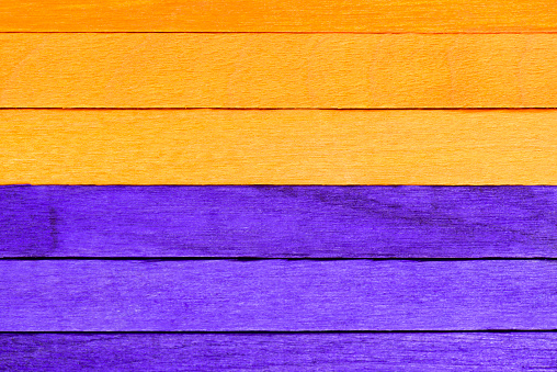 Purple and orange painted boards for Halloween background. Two-tone striped wooden textured background. Horizontal wooden textured boards divided into orange and purple.