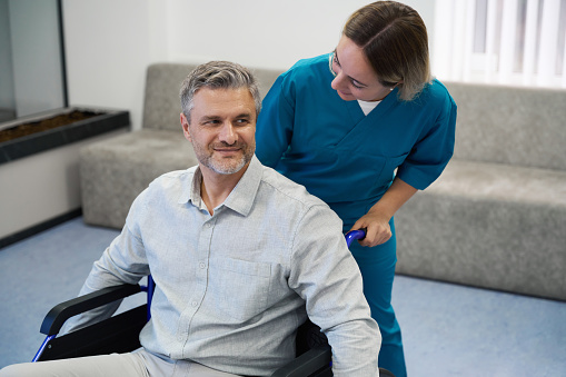 Woman in a blue uniform communicates with a patient who is in a wheelchair